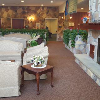 A cozy living room with sofas, a fireplace, and decorative plants.
