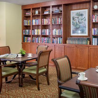 A cozy reading room with bookshelves, tables, and chairs.