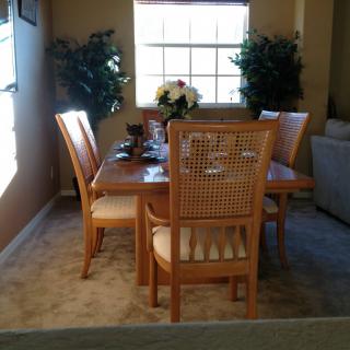 A cozy dining room with a wooden table and chairs, adorned with decorative plants and a window letting in natural light.