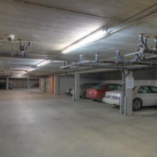 An indoor parking garage with several parked cars and overhead lighting.