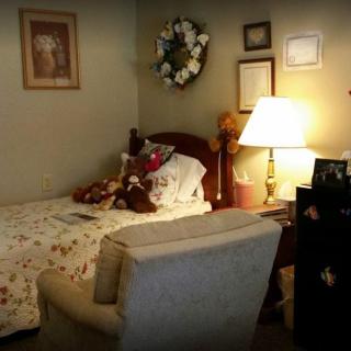 A cozy bedroom with a bed, armchair, and warm lighting.