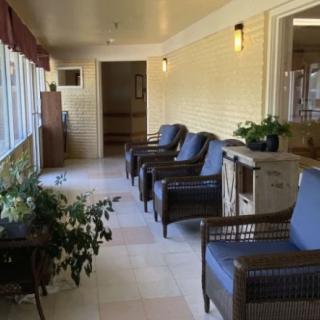 A cozy indoor seating area with chairs and potted plants along a hallway with large windows.