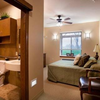 A cozy bedroom with an adjoining bathroom, featuring a bed, window, and stylish lighting.