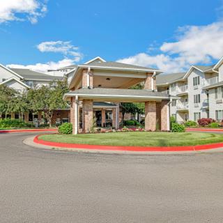 A large residential building with landscaped surroundings under a partly cloudy sky.