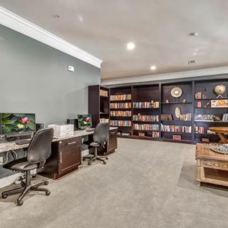 A spacious home office with bookshelves and a dual desk setup.