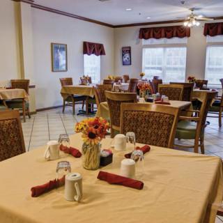 A cozy dining room with neatly set tables, adorned with flowers and napkins.