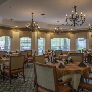 An elegant dining room with chandeliers and neatly arranged tables and chairs.