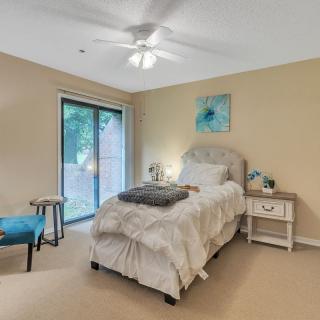 A cozy bedroom with a single bed, nightstand, chair, and sliding glass door leading outside.