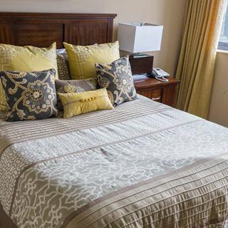 A cozy bedroom with a neatly arranged bed and decorative pillows.