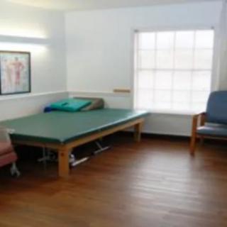 A therapy room with a treatment table and chairs in a medical facility.