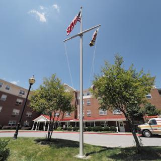 Flags flying in front of a building under a clear blue sky.
