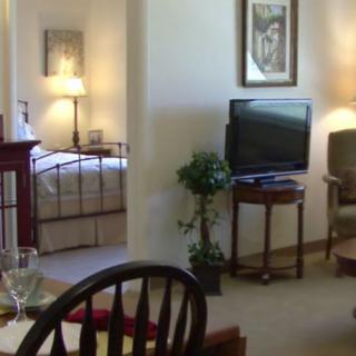 A cozy interior featuring a living room and adjacent bedroom with comfortable furniture and warm lighting.