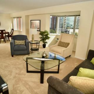 A modern living room with stylish furniture and a cityscape view through large windows.