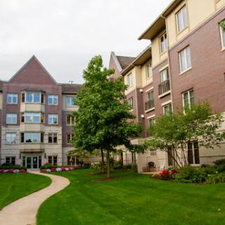 A beautifully landscaped residential building with lush green lawns and trees.