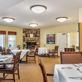 A cozy dining room with neatly arranged tables and a central fireplace, creating a welcoming atmosphere.