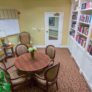 A cozy reading room with bookshelves, a round table, and chairs.