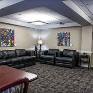 A well-furnished waiting room featuring comfortable seating and colorful artwork on the walls.