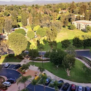 A scenic aerial view showcasing a mix of trees, a parking lot, and buildings under clear skies.
