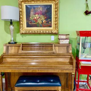 A beautifully arranged corner featuring a wooden piano, a decorative lamp, and an artwork on a vibrant green wall.
