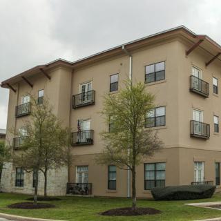 A modern apartment building with balconies and well-maintained landscaping.