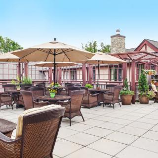A cozy outdoor patio with wicker furniture and umbrellas, perfect for dining or relaxing in a charming restaurant setting.