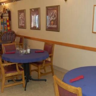 A cozy restaurant dining area with tables covered in blue tablecloths and framed art on the walls.
