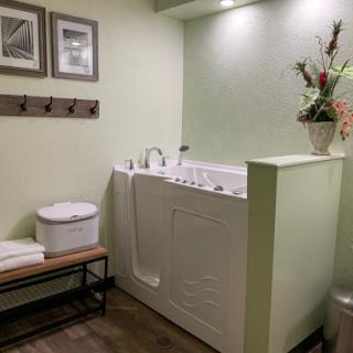 A tranquil bathroom featuring a luxurious bathtub, green walls, and calming decor.