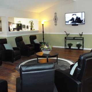 A modern living room with leather chairs arranged around a TV, featuring wood flooring and contemporary decor.