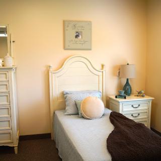 A cozy, well-decorated bedroom featuring a single bed, nightstand, and soft color palette.