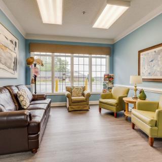 A cozy living room with a sofa, two armchairs, and large windows allowing abundant natural light.