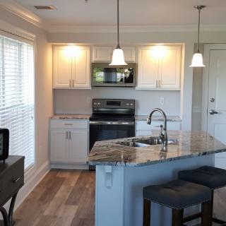 A modern kitchen with white cabinets, stainless steel appliances, and pendant lighting.