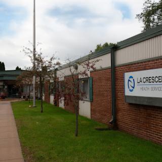 A view of a modern building with landscaped surroundings, featuring a clear sign.
