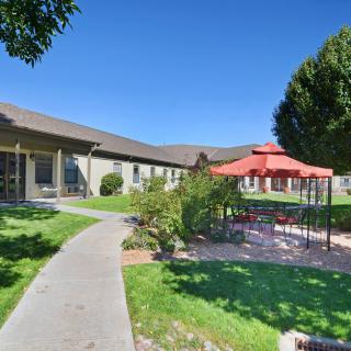 A sunny day in a landscaped area with a large building, gazebo, pathway, and green lawns.