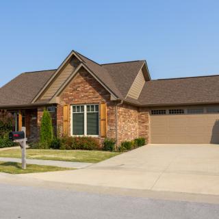 A suburban brick house with a driveway and attached garage.