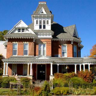 A beautiful Victorian-style house with a large porch and turret.