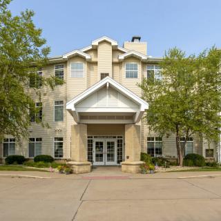 A front view of a residential building with trees flanking the entrance.