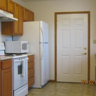 A tidy kitchen with wooden cabinets, a white refrigerator, and appliances.