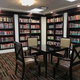 A cozy library corner with a table surrounded by chairs, ideal for reading and studying.