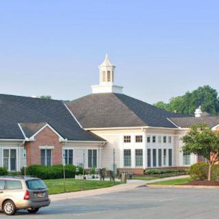 A suburban building with a cupola on its roof, situated next to a road with a parked car.
