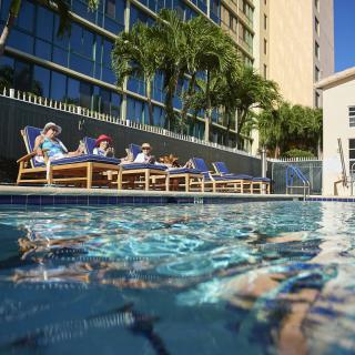 Guests relaxing by the hotel swimming pool under the sun.