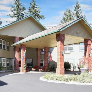 An inviting building entrance with a covered driveway and surrounded by trees.