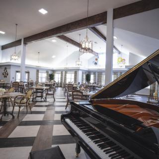 An elegant restaurant interior featuring a grand piano and neatly arranged tables and chairs.