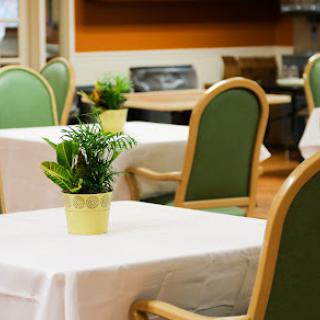 A cozy dining area featuring tables with white tablecloths and small potted plants.