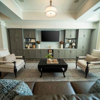 A modern living room featuring a comfortable seating area with neutral-toned furniture, built-in shelves, and a television.