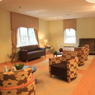 A cozy living room featuring comfortable seating with floral-patterned chairs and warm natural light.