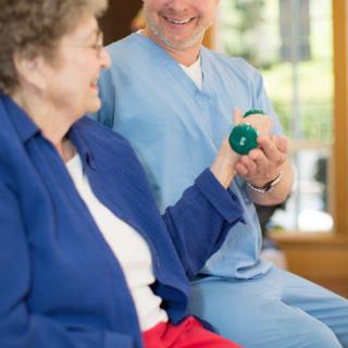 A senior citizen engaging in physical therapy with the help of a healthcare professional.