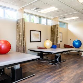 A well-equipped therapy room featuring exercise balls and adjustable tables, designed for rehabilitation and fitness.