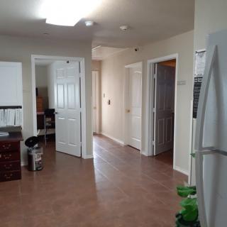 A view of an apartment interior showing a kitchen area with a refrigerator and multiple doors leading to other rooms.