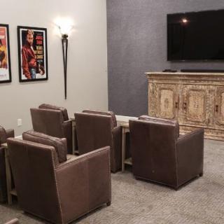 A cozy home theater setup with leather seats and wall-mounted movie posters.