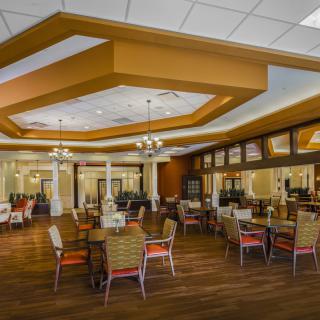 A spacious restaurant dining area with elegant lighting and neatly arranged tables and chairs.